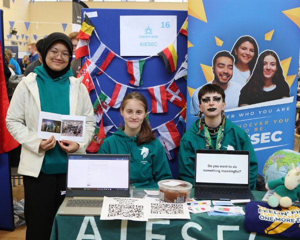 Committee Members for AISEC Society pose at the Welcome Fayre with flags from all over the world in the background