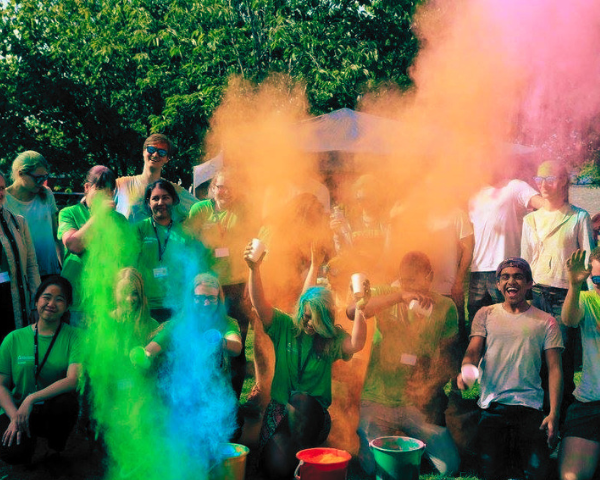 Students pose seated and standing while green blue and yellow coloured smoke flies over them